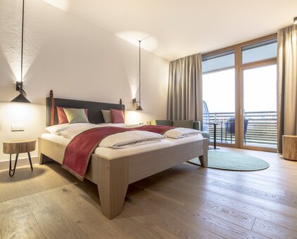 Helles Doppelzimmer mit Holzboden, großem Bett, Balkon und Natur-Ausblick
