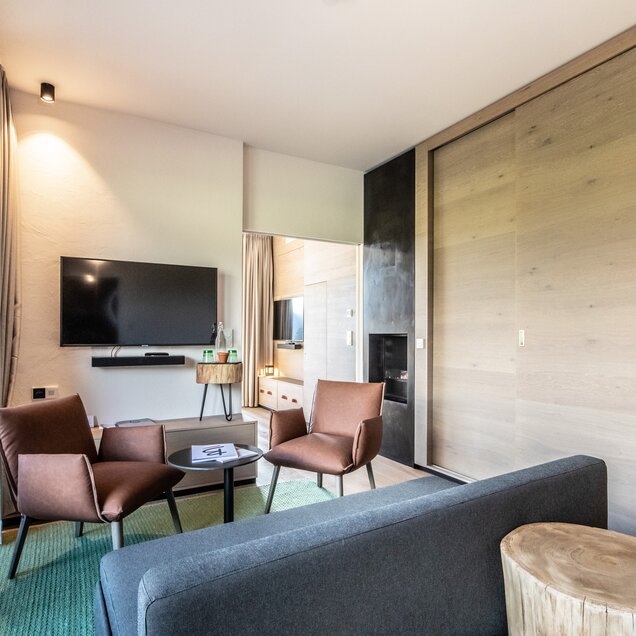 Bright junior suite with sofa, armchair, TV and wooden elements